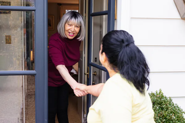 A Papa Pal greets an older adult at her front door.